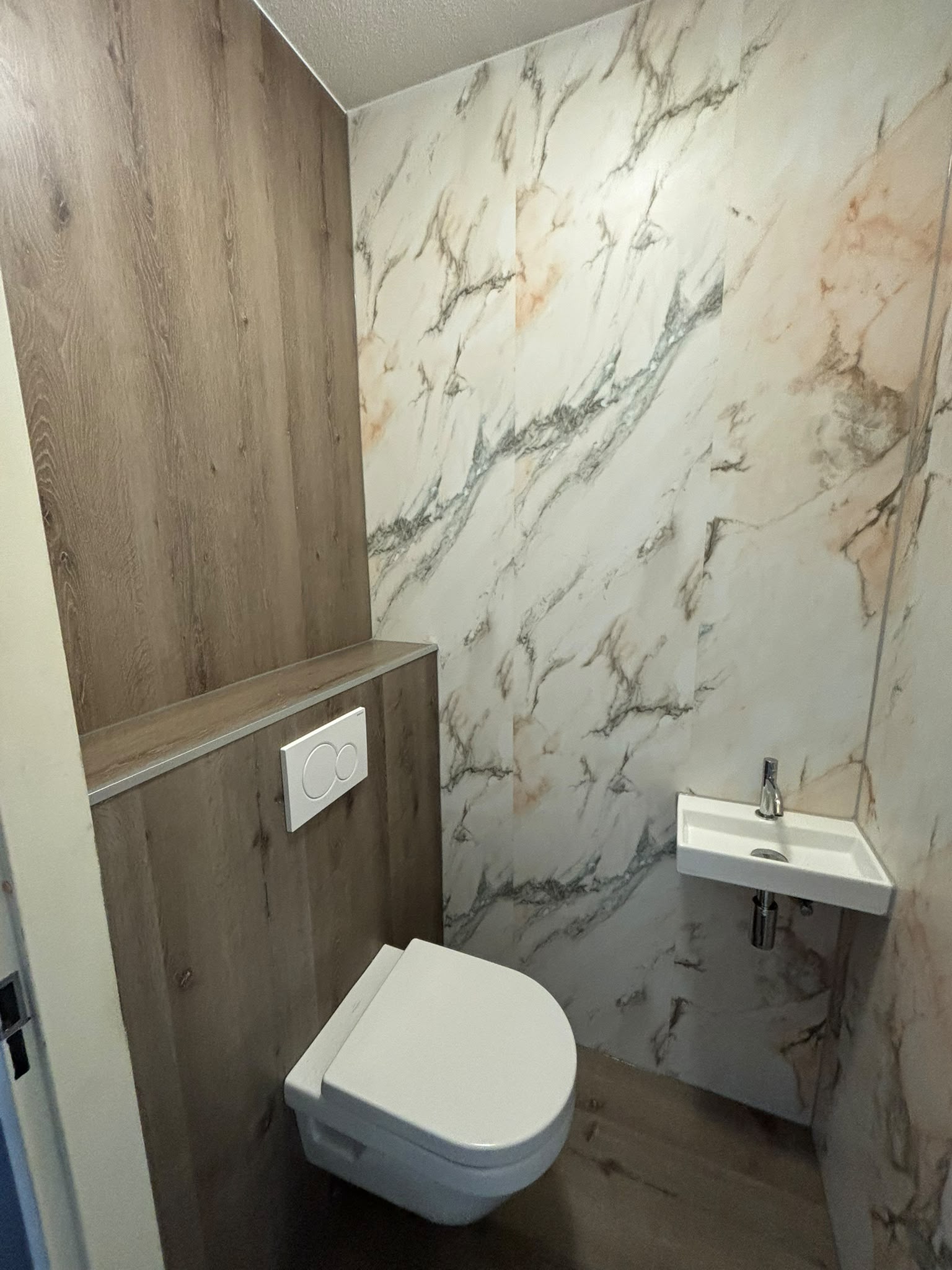 Wc renovatie met houtlook en witte marmer wandpanelen Wc renovatie met houtlook en witte marmer wandpanelen